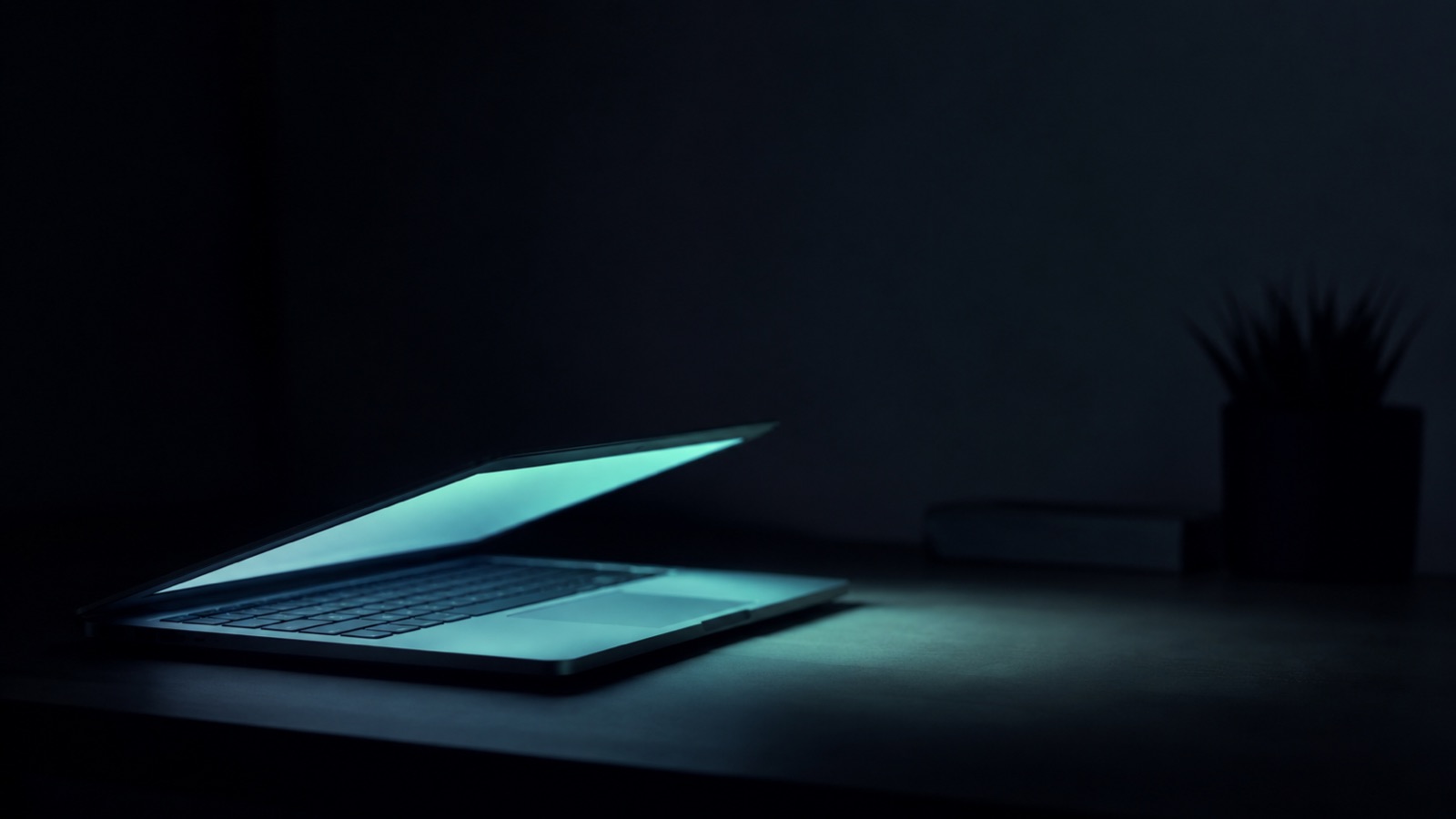 A partially closed laptop glowing in a dim room