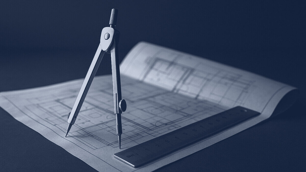 A drafting compass and ruler on a folded technical drawing