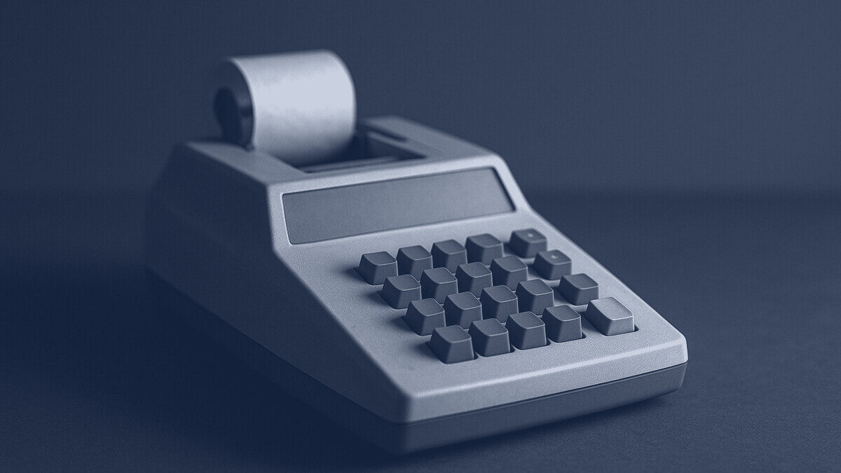 A vintage desk calculator with a paper roll